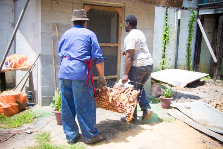 The cooked hog being taken into the back of the kitchen to be taken apart.