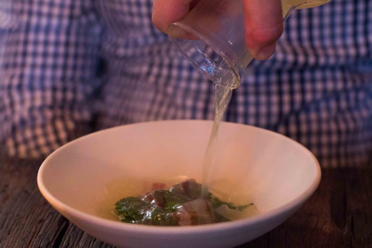 Fish broth poured over top a plate of spring vegetables.